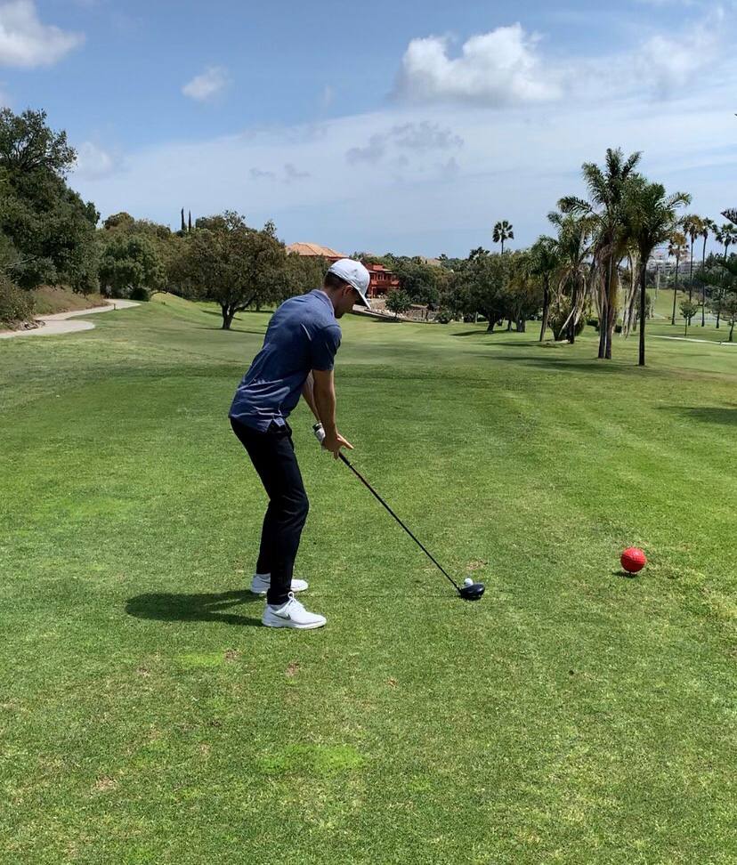 Robin spelar golf på en solig dag med palmer i bakgrunden