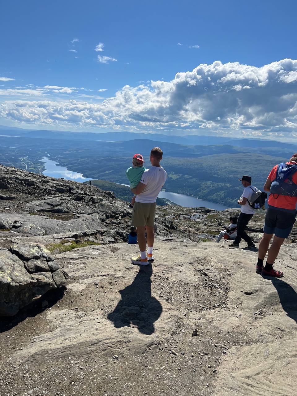 Robin på en bergstopp med sitt barn och utsikt över dalar och sjöar