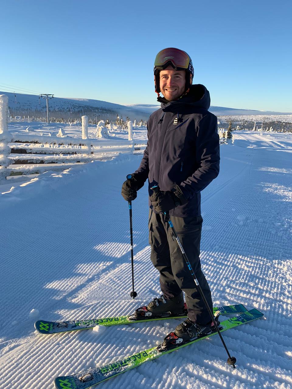 Robin i skidbacken en solig vinterdag med snötyngda granar
